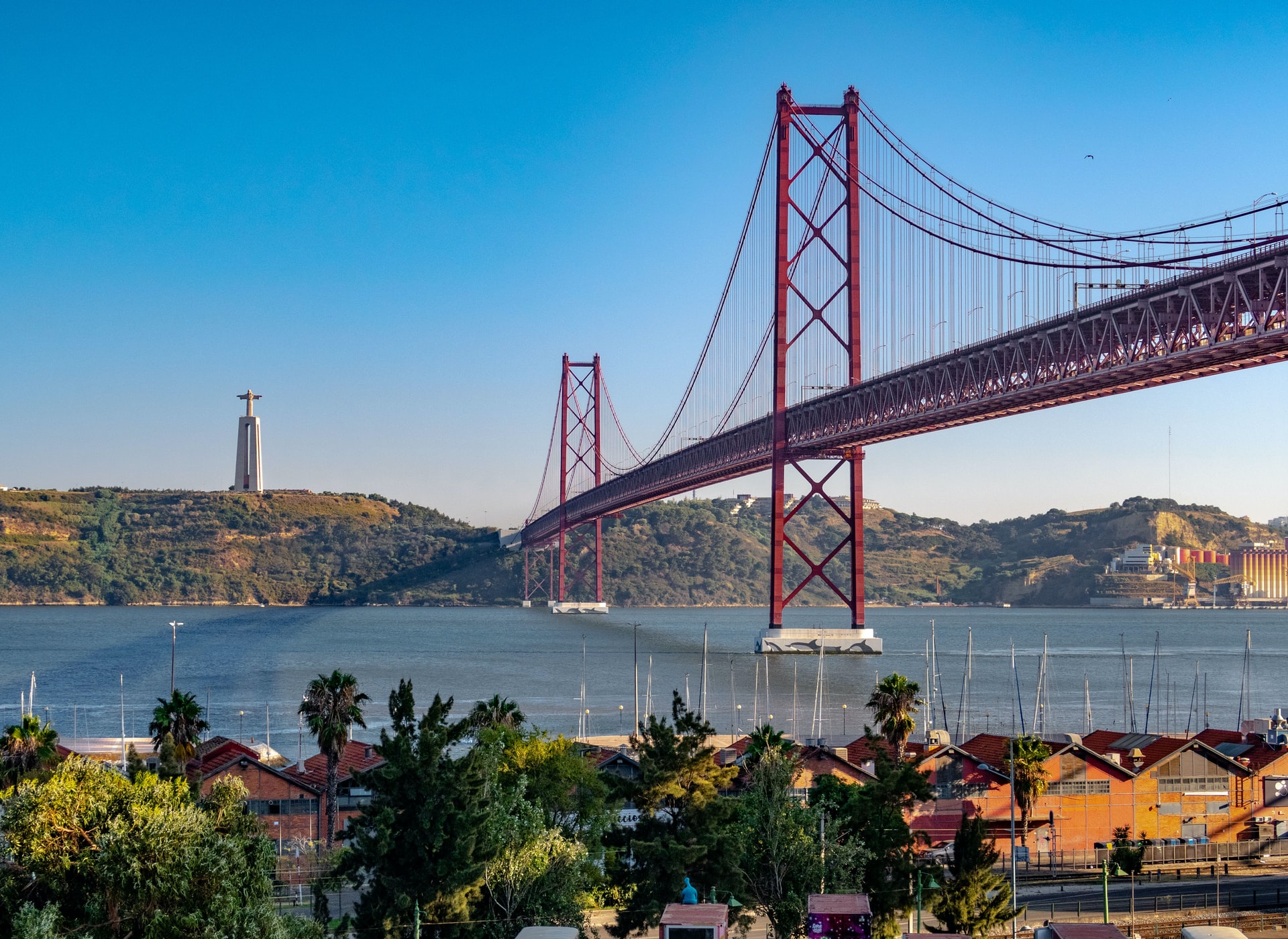 Bild von der Brücke 25 de Abril in Lissabon, Portugal, mit Blick über den Tejo auf die Statue Cristo Rei